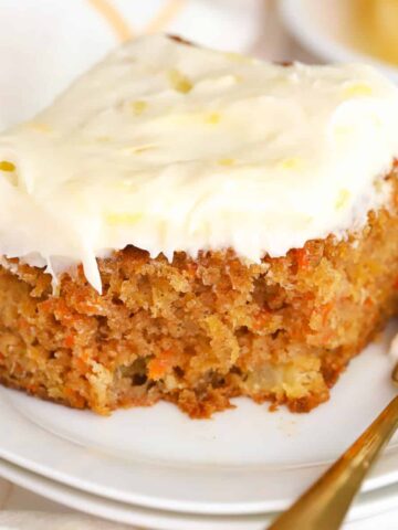 Slice of Pineapple Carrot Cake on a white plate with a gold fork