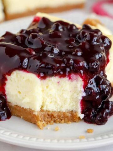 Closeup of a cheesecake bar topped with blueberry sauce