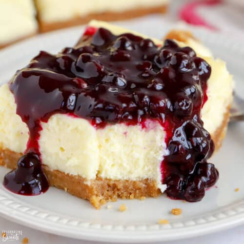 Closeup of a cheesecake bar topped with blueberry sauce