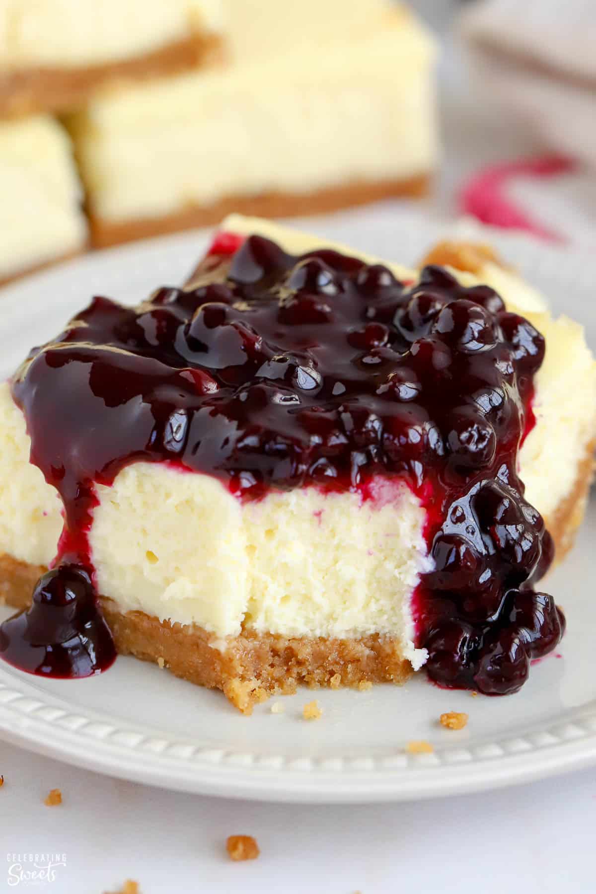 Cheesecake bar on a white plate covered with blueberry sauce