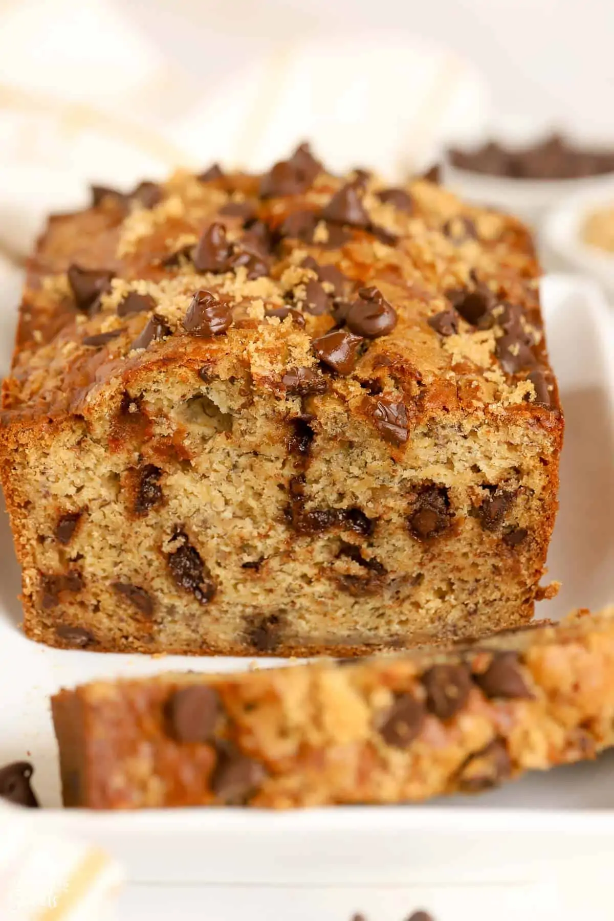Closeup of a loaf of chocolate chip banana bread on a white plate.