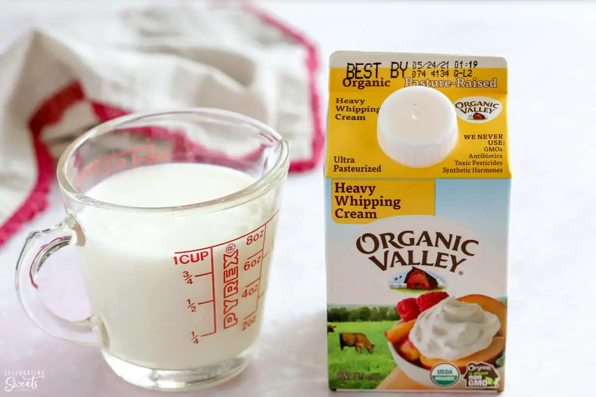 Heavy cream in a carton and milk in a glass measuring cup