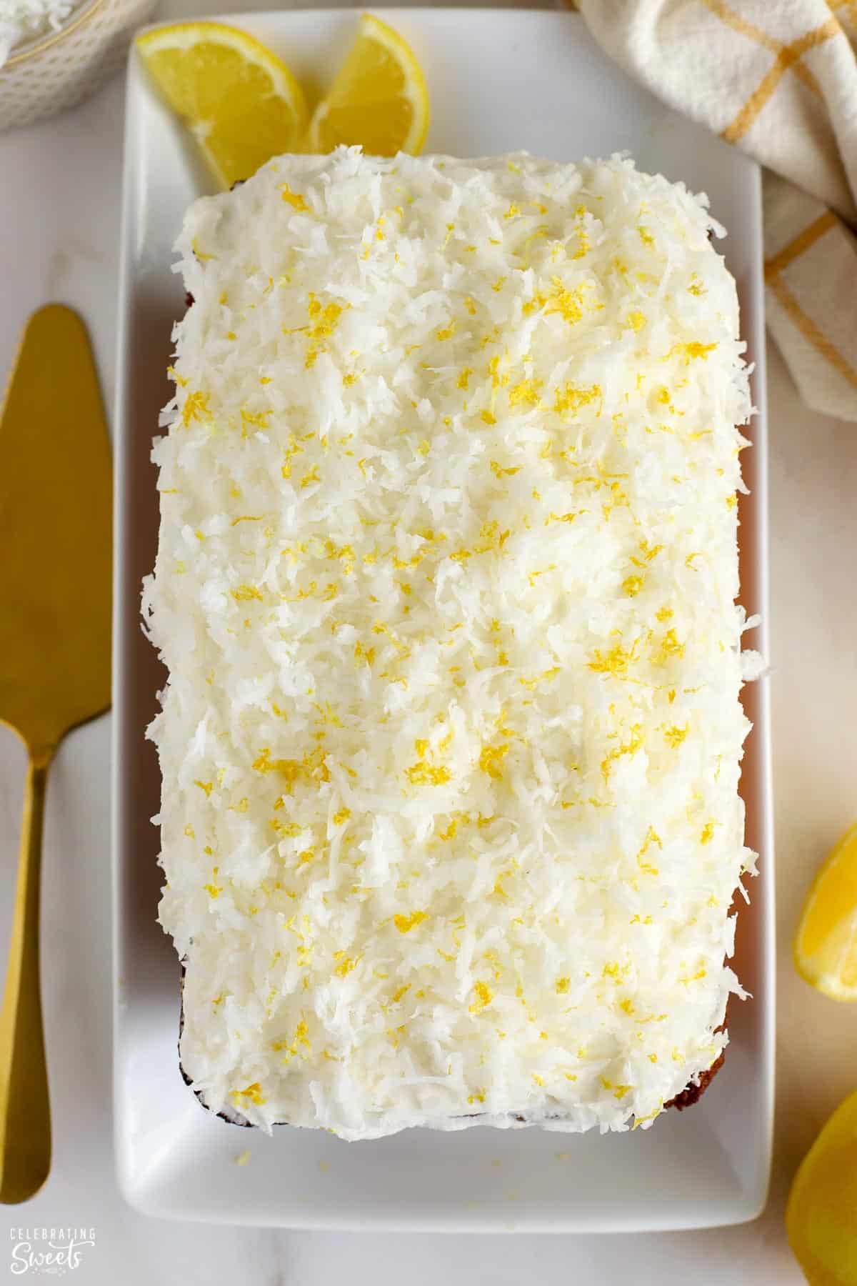 Overhead shot of a lemon coconut cake topped with frosting, shredded coconut, and lemon zest