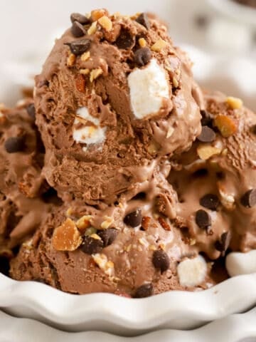 Closeup of a white bowl filled with scoops of rocky road ice cream.