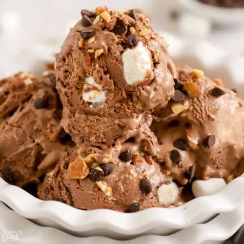 Closeup of a white bowl filled with scoops of rocky road ice cream.