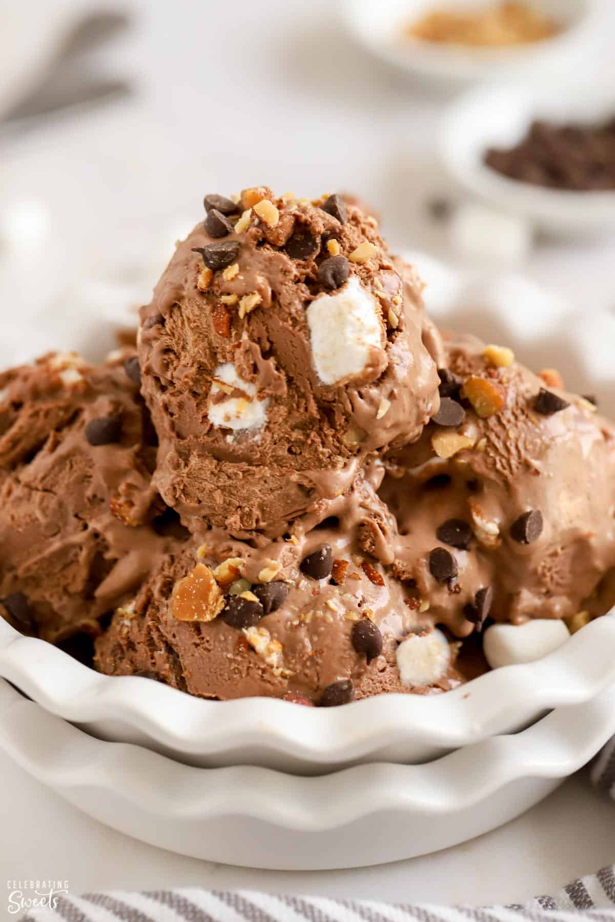 Closeup of white bowl filled with scoops of rocky road ice cream.