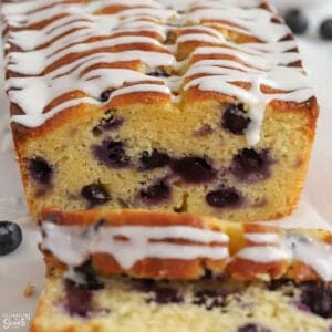 Closeup of a loaf of blueberry bread topped with white icing.