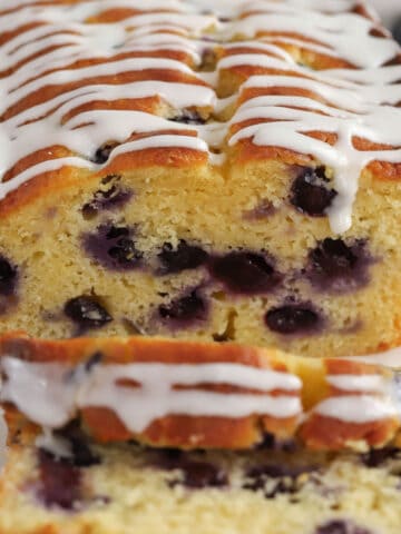 Closeup of a loaf of blueberry bread topped with white icing.