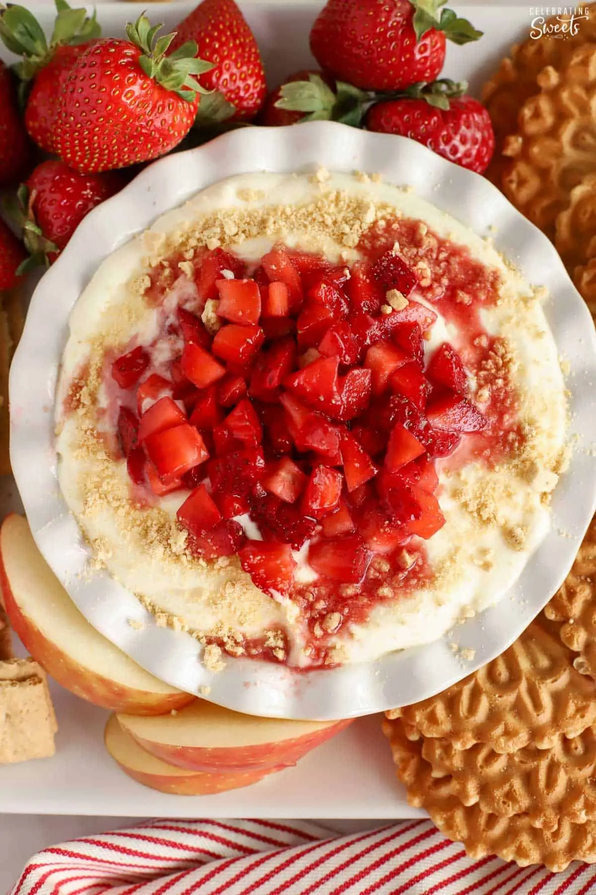Cheesecake dip in a white bowl topped with strawberries