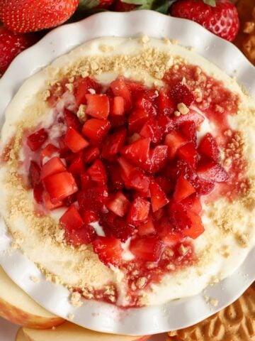 Cheesecake dip in a white bowl topped with strawberries