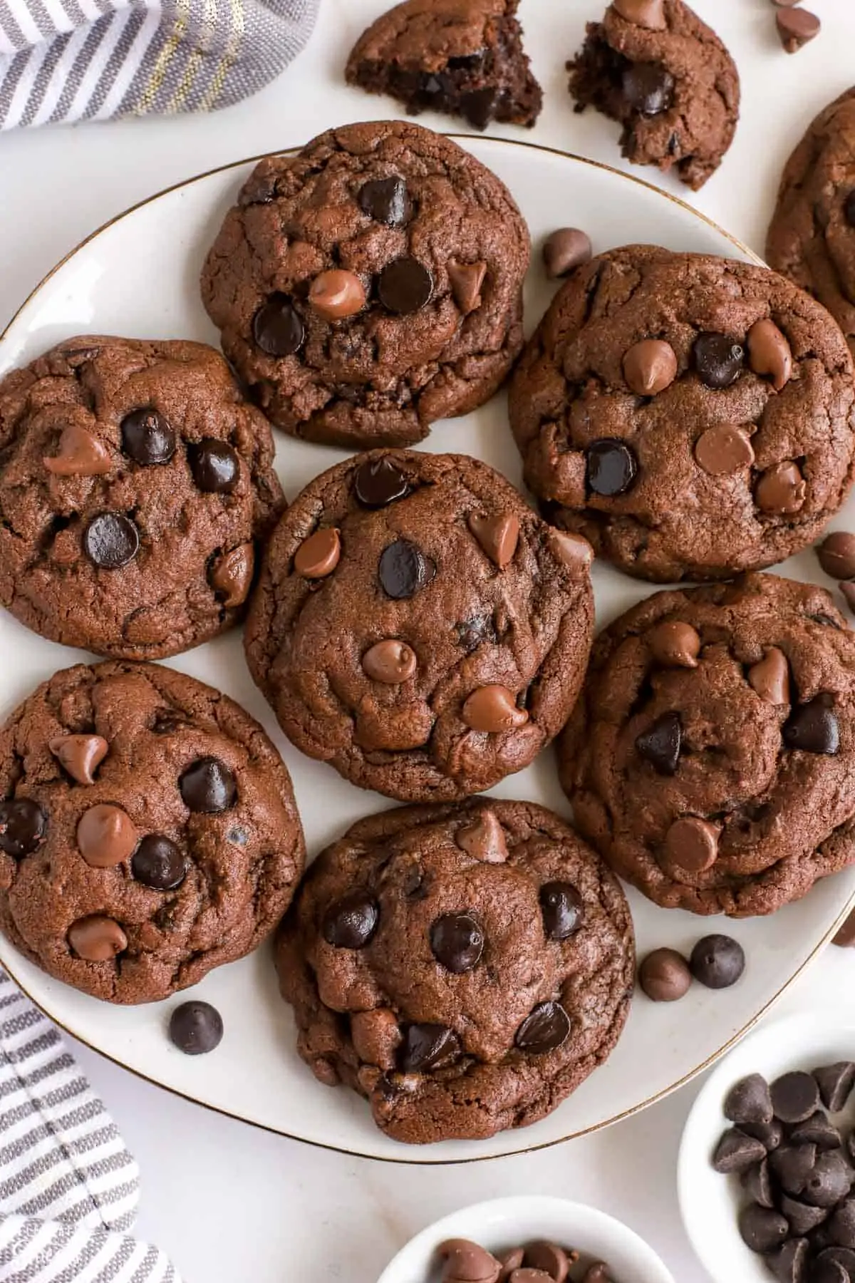 White plate with chocolate cookies topped with chocolate chips.