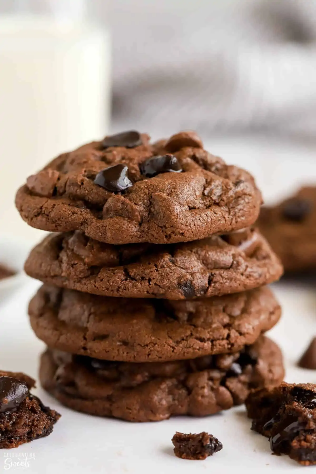 Stack of four chocolate cookies with milk in the background