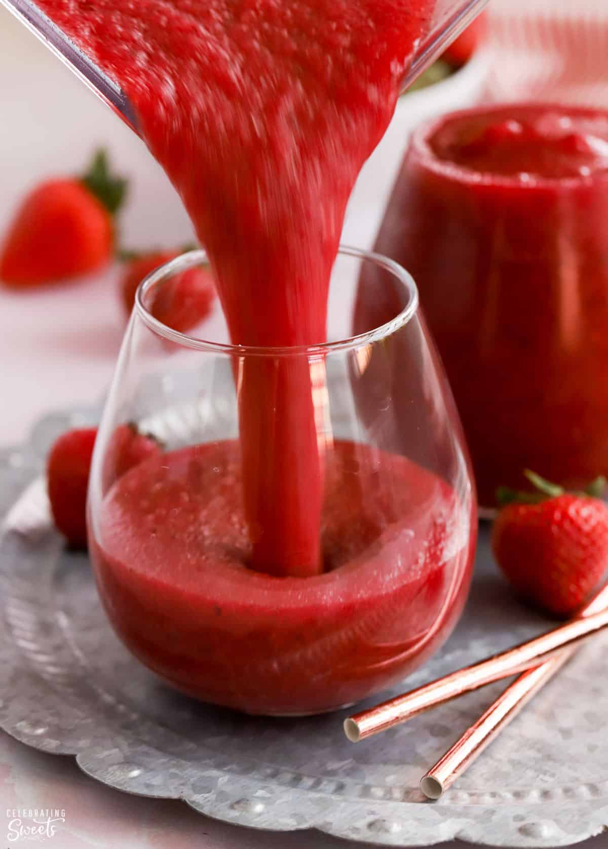 Dark red Frosé wine slushies being poured into a glass on a silver tray.