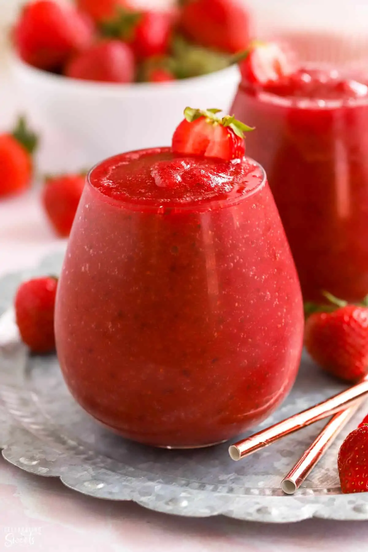 Dark red Frosé wine slushies in a glass garnished with strawberries.