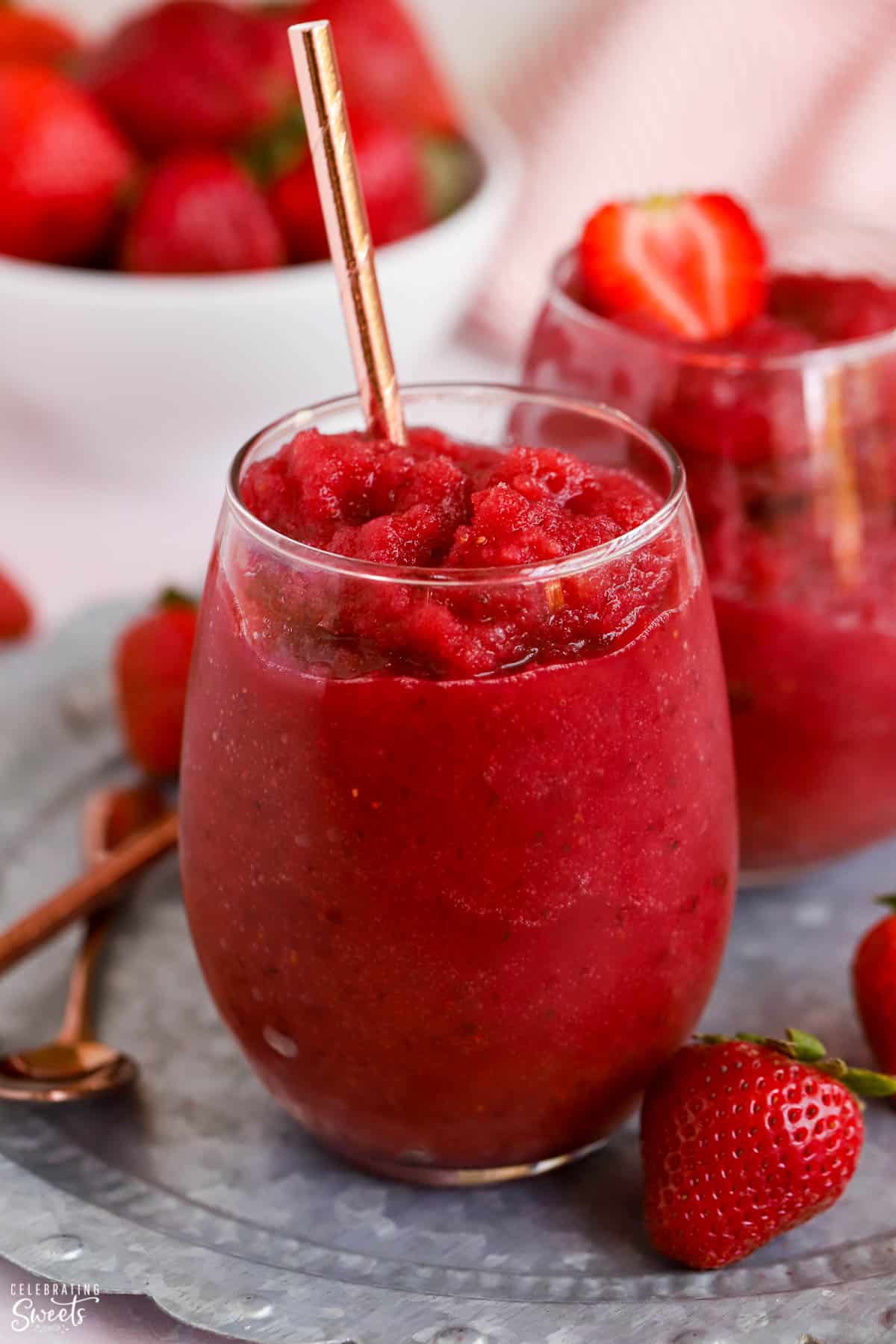Dark red Frosé wine slushies in a glass garnished with strawberries.