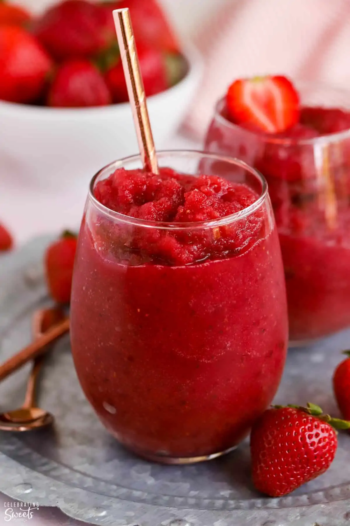 Dark red Frosé wine slushies in a glass garnished with strawberries.