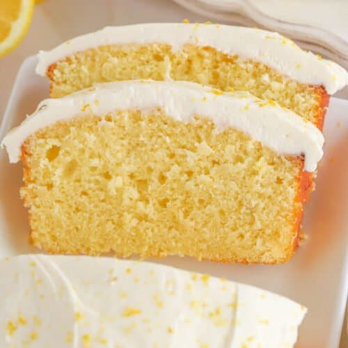 Two slices of lemon loaf cake topped with frosting and lemon zest.