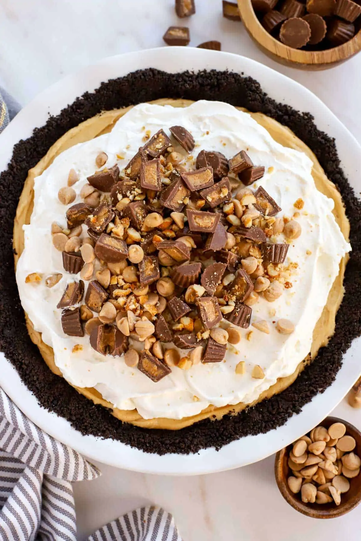 Overhead shot of peanut butter pie in a white pie plate topped with peanut butter cups and peanut butter chips.