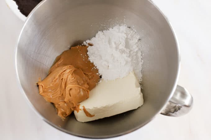 Cream cheese, powdered sugar, and peanut butter in a stainless mixing bowl.