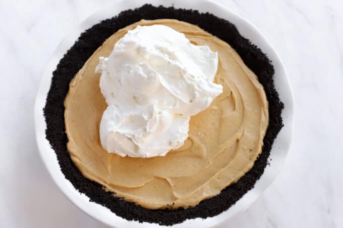 Whipped cream on top of peanut butter filling in an Oreo crust.