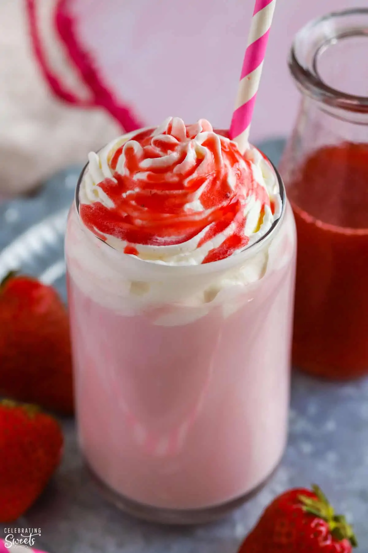 Glass of Strawberry Milk topped with whipped cream and strawberry syrup.