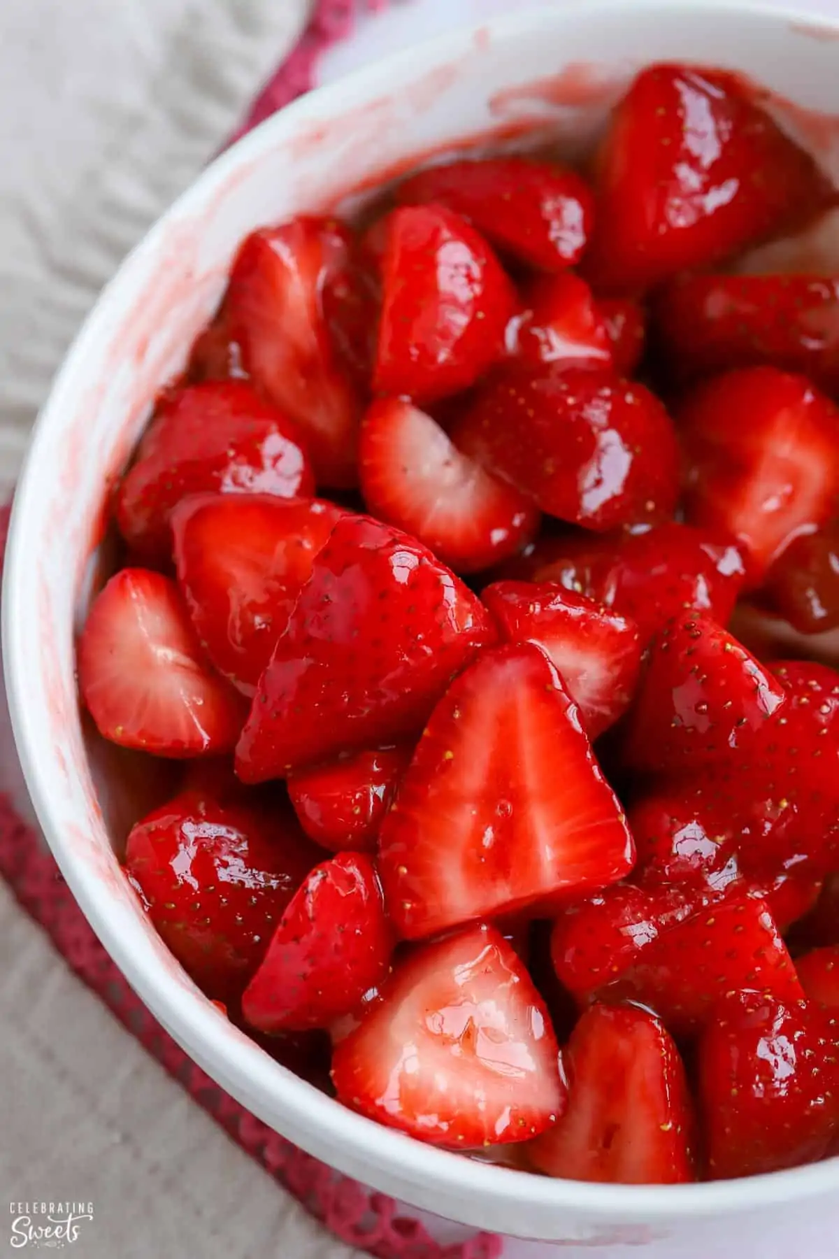 Bowl of sliced strawberries covered in jam.