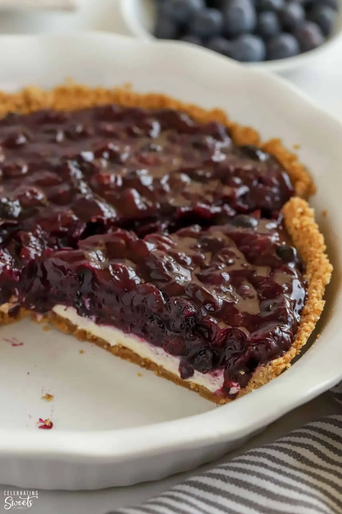 Blueberry Pie in a graham cracker crust with a white pie plate.