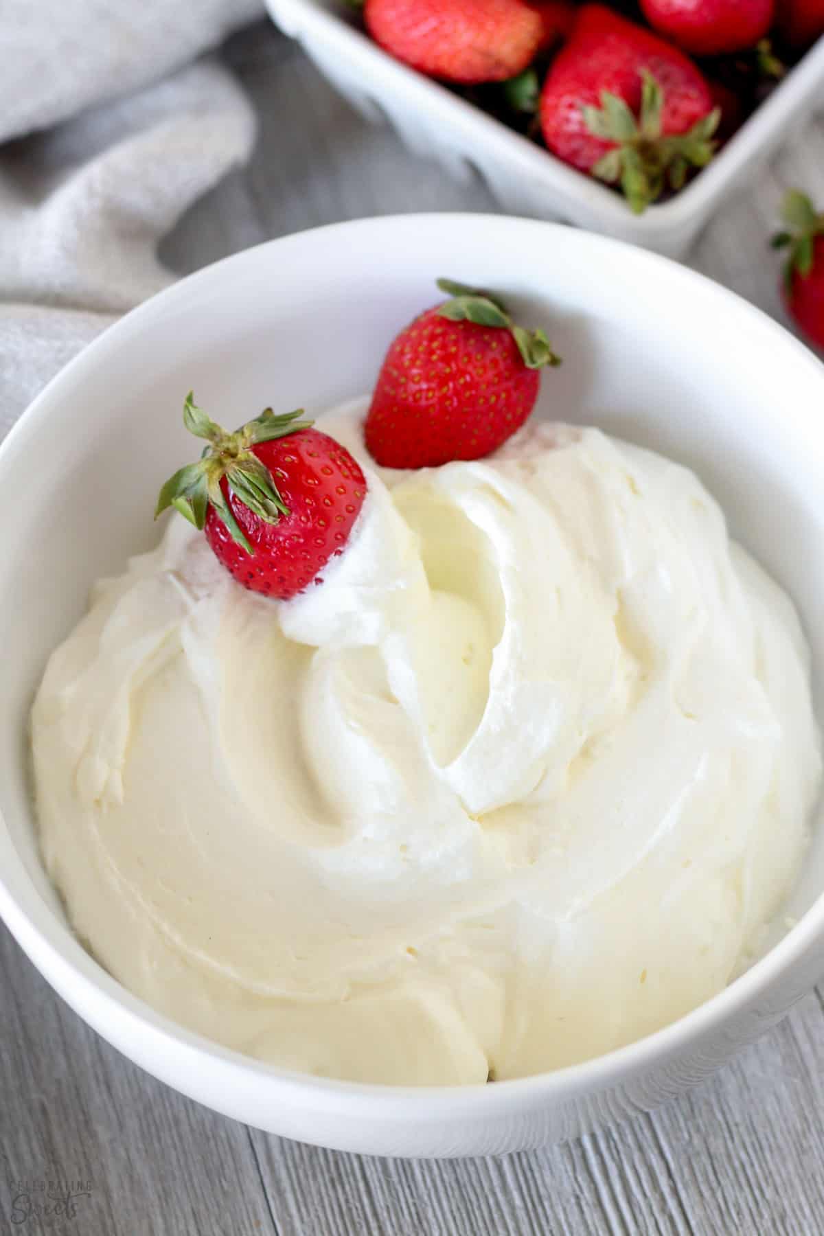 Whipped cream in a white bowl with strawberries.