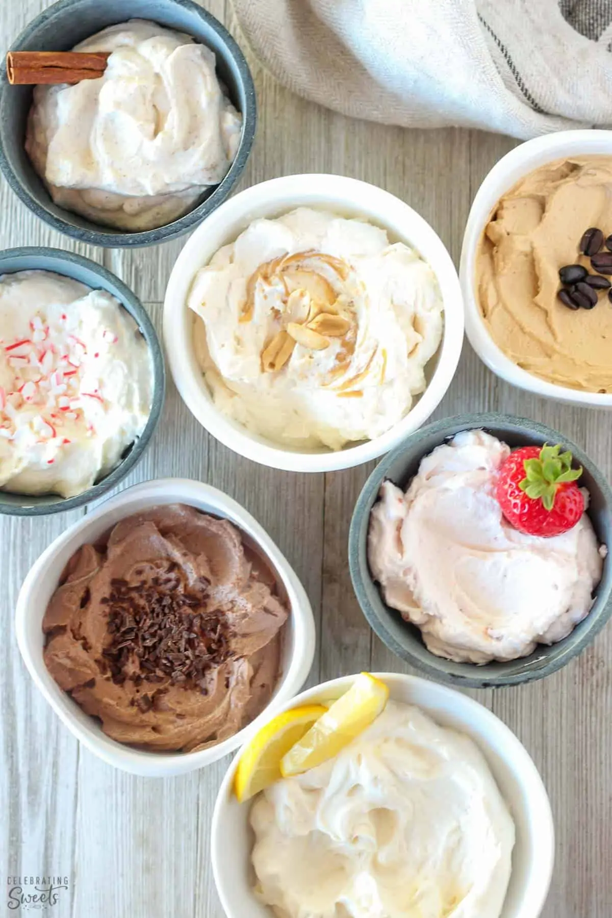 Seven bowls of flavored whipped cream on a wooden board