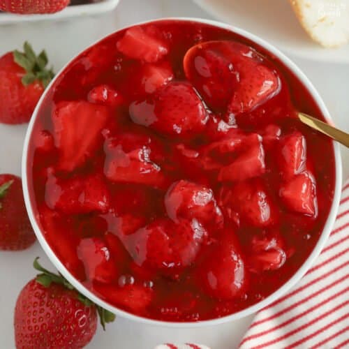 Strawberry sauce in a white bowl with a gold spoon