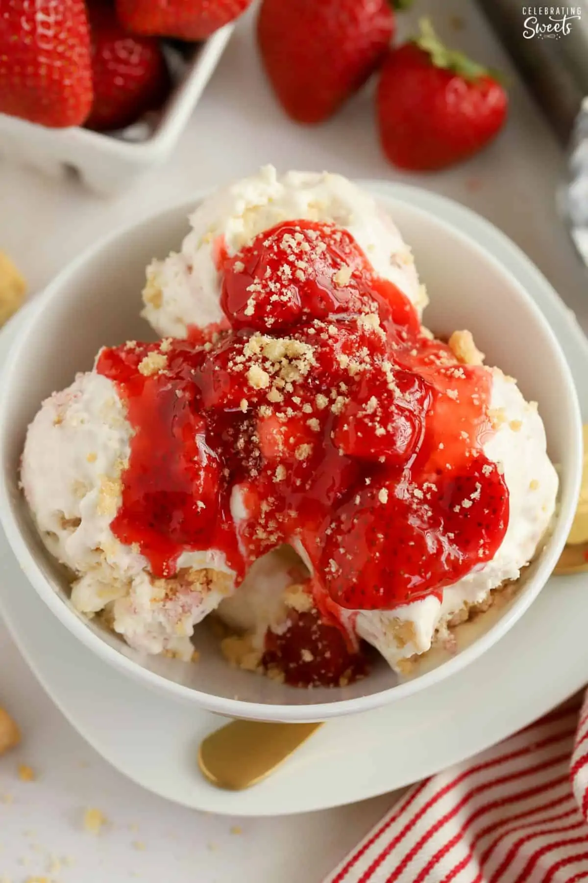 Strawberry sauce on ice cream in a white bowl with a gold spoon.