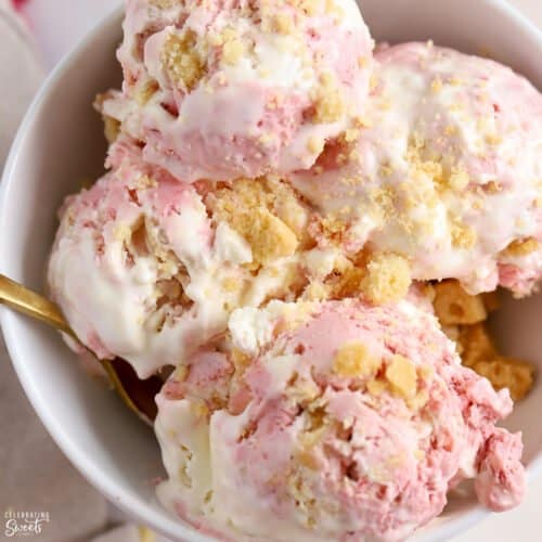 Scoops of strawberry shortcake ice cream in a white bowl.