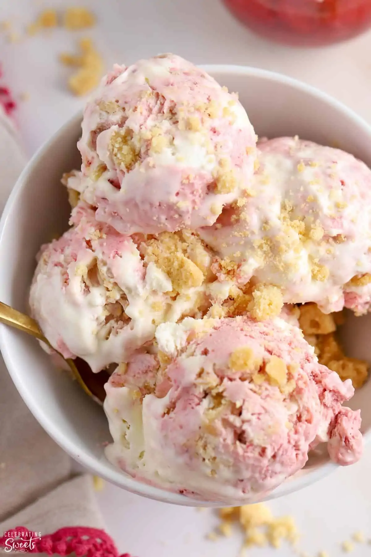 Scoops of strawberry shortcake ice cream in a white bowl.