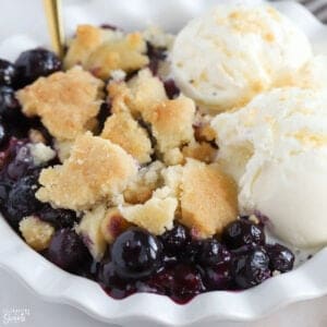 Closeup of blueberry cobbler topped with ice cream.