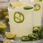 Spicy Margarita in a glass on a tray garnished with lime and jalapeno slices.