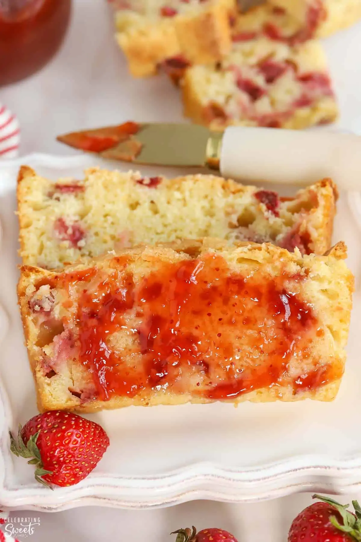 Two slices of strawberry bread on a white plate topped with strawberry jam.