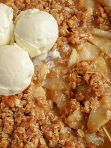 Closeup of Apple Pear Crisp topped with scoops of vanilla ice cream.