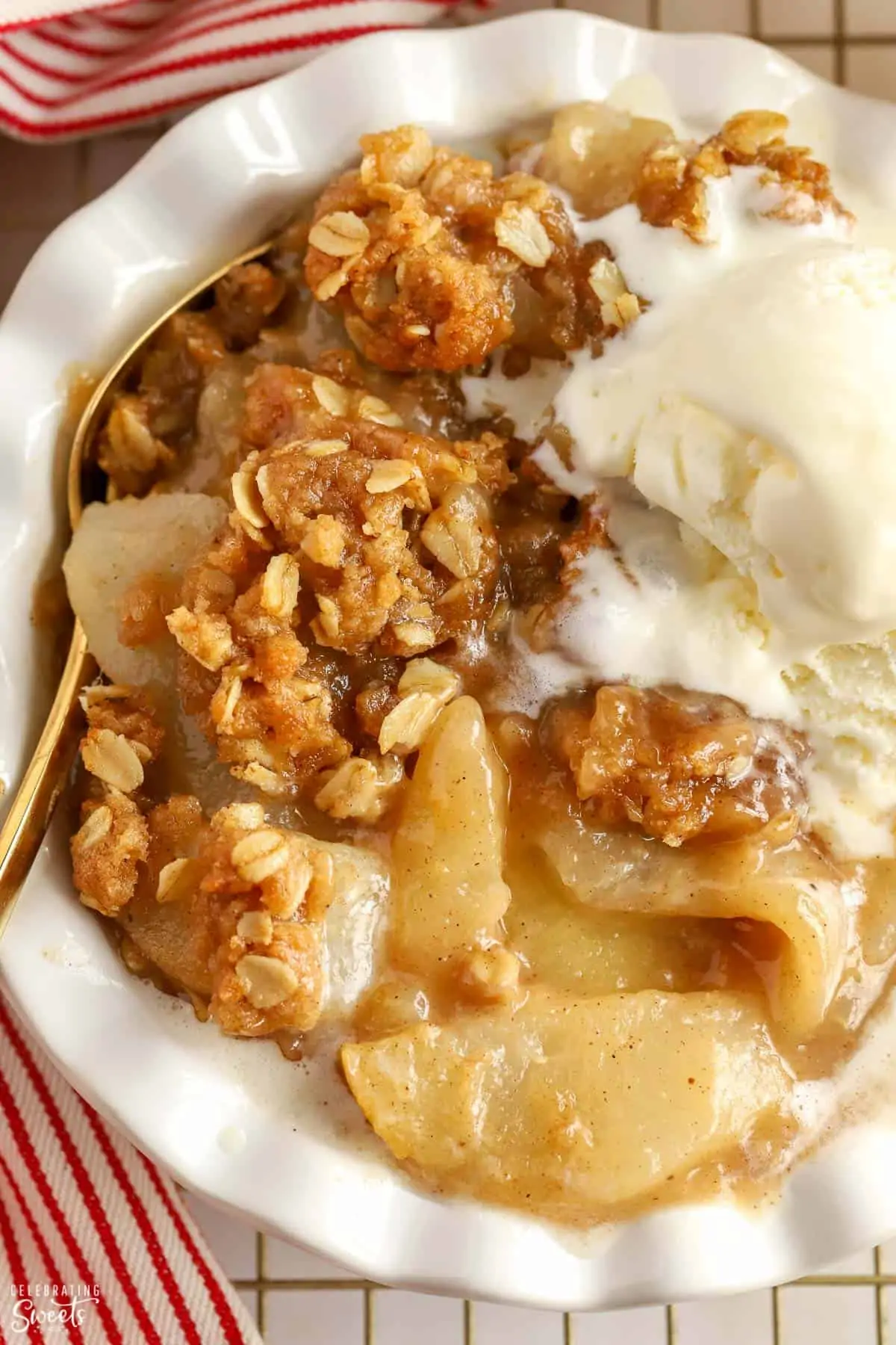 Closeup of Apple Pear Crisp topped with scoops of vanilla ice cream in a white bowl.
