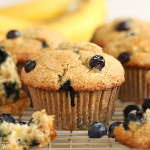 Closeup of blueberry banana muffins on a wire rack with bananas in the background.