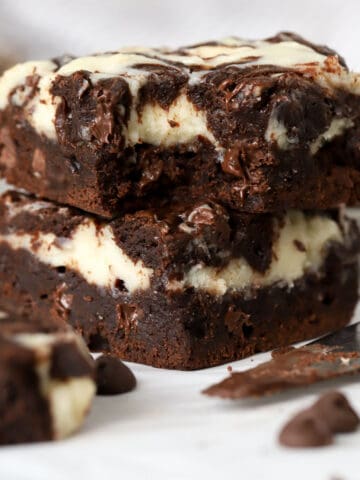 Stack of two cream cheese brownies on a piece of parchment.