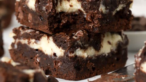 Stack of two cream cheese brownies on a piece of parchment.