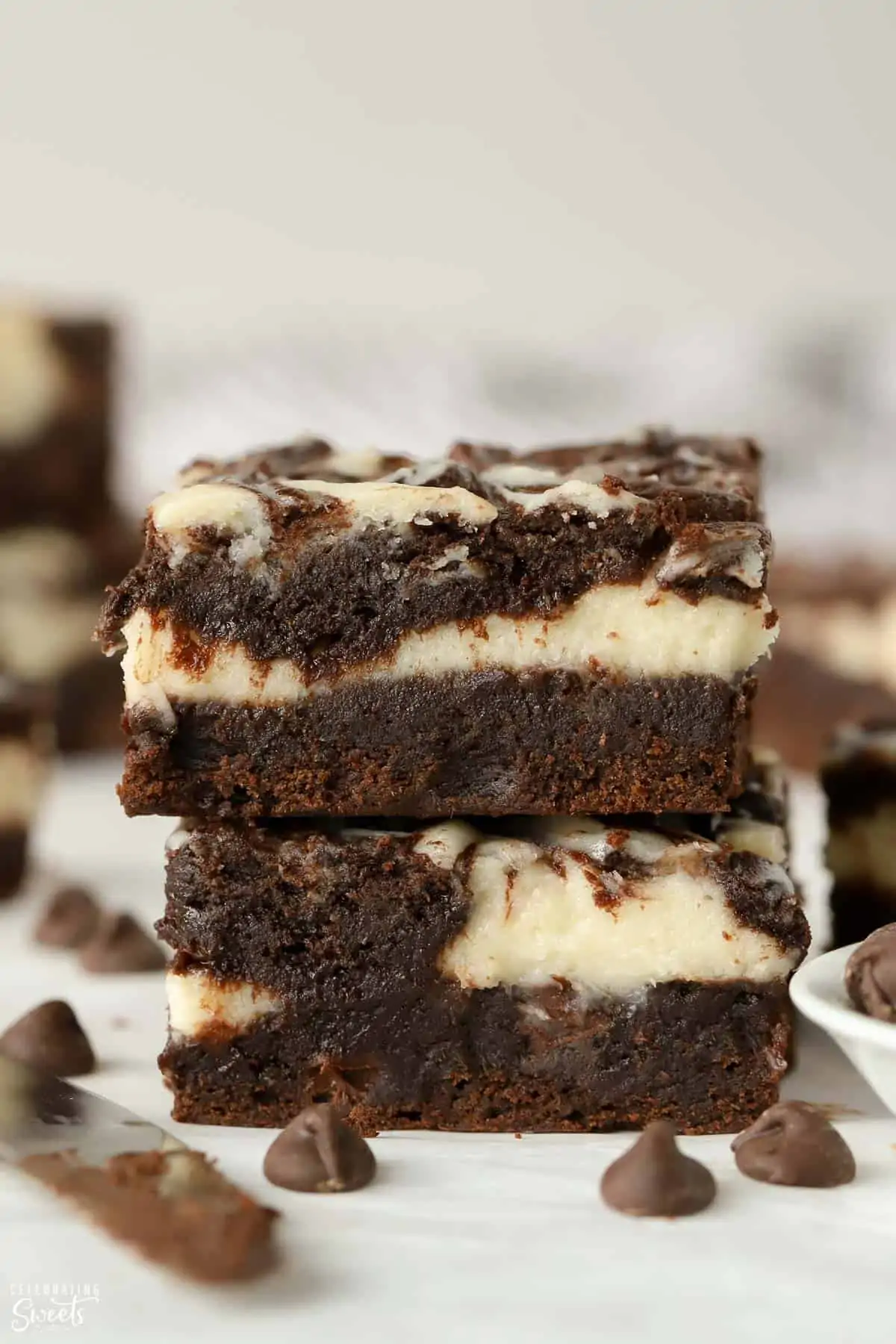 Stack of two cream cheese brownies on parchment paper.