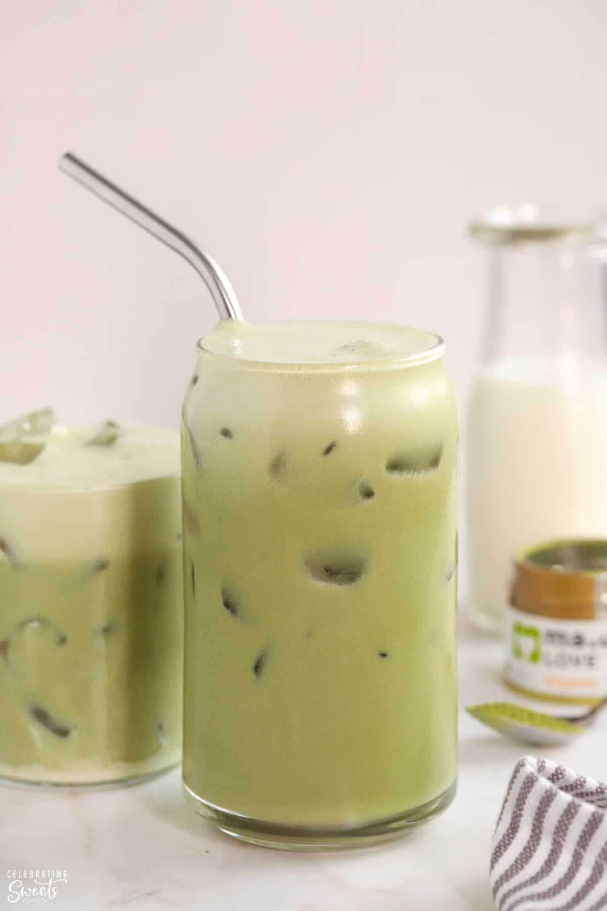 Closeup of an iced matcha latte in a glass with a stainless straw