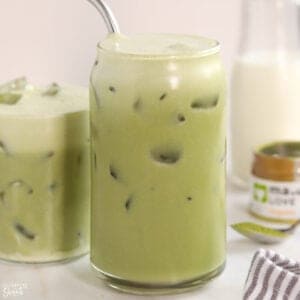 Closeup of an iced matcha latte in a glass with a stainless straw