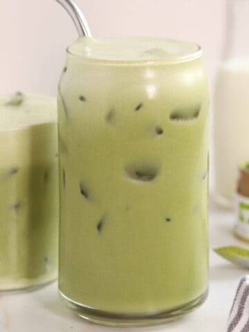 Closeup of an iced matcha latte in a glass with a stainless straw