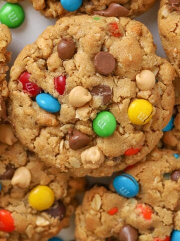 Closeup of Monster Cookies laying on parchment paper topped with M&M's and chocolate chips