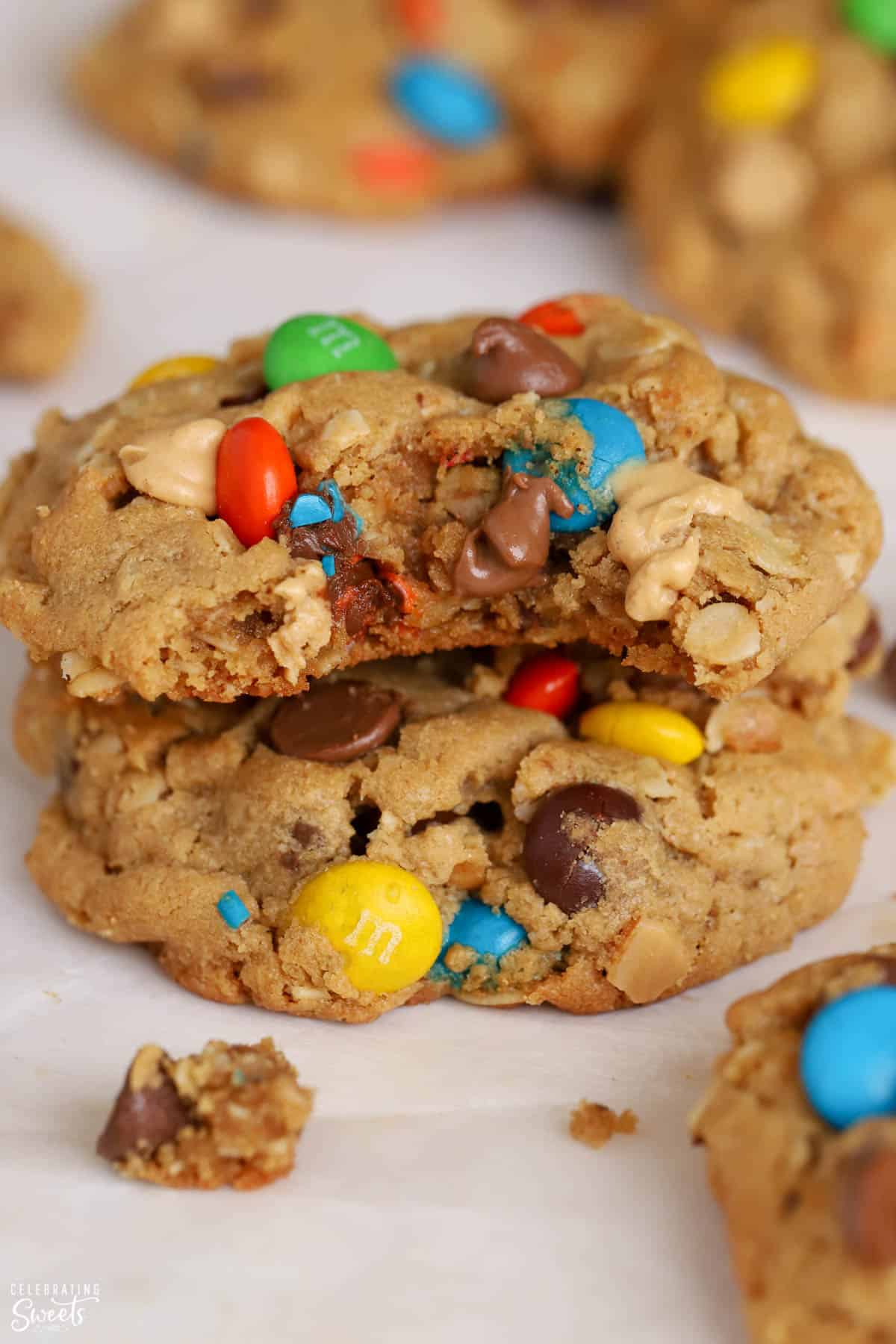 Two Monster Cookies stacked on top of each other with a bite taken out of the top cookie.