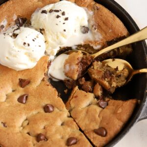 Chocolate chip skillet cookie in a cast iron skillet topped with ice cream