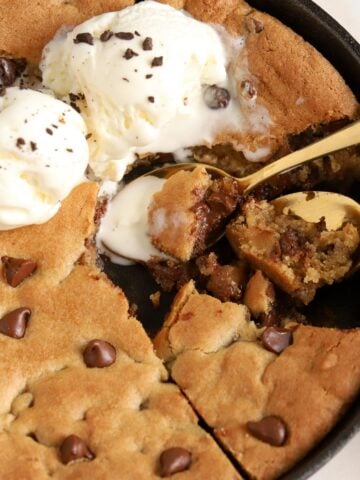 Chocolate chip skillet cookie in a cast iron skillet topped with ice cream