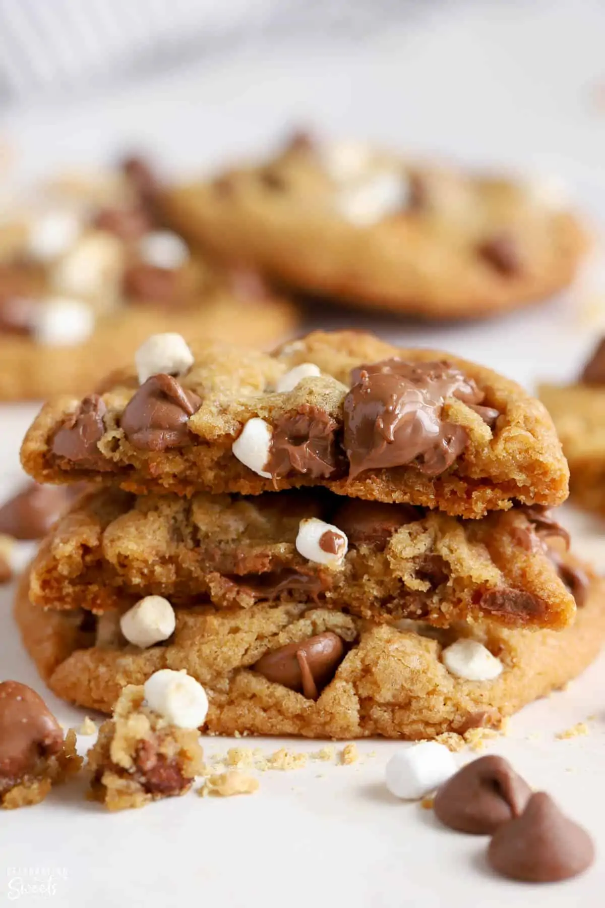 Stack of s'mores cookies surrounded by marshmallows and chocolate chips.